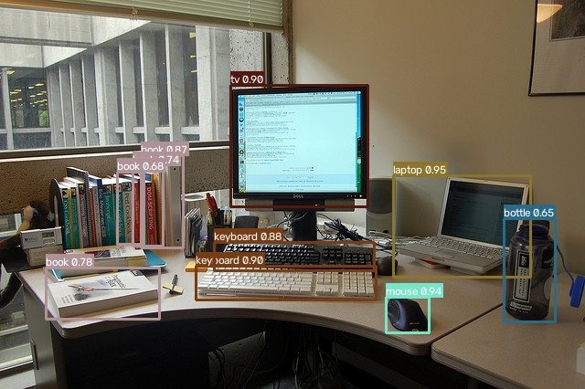yolox-pylon-xl on a real office desk: monitor, two keyboards, mouse, laptop, bottle and a shelf of books detected