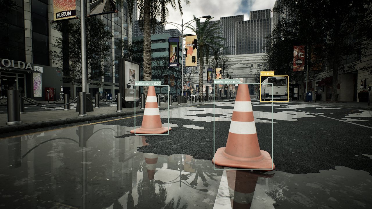 yolox-pylon-xl on a wet synthetic boulevard: two traffic cones detected at 0.98 and 0.97 confidence and a bus at 0.96