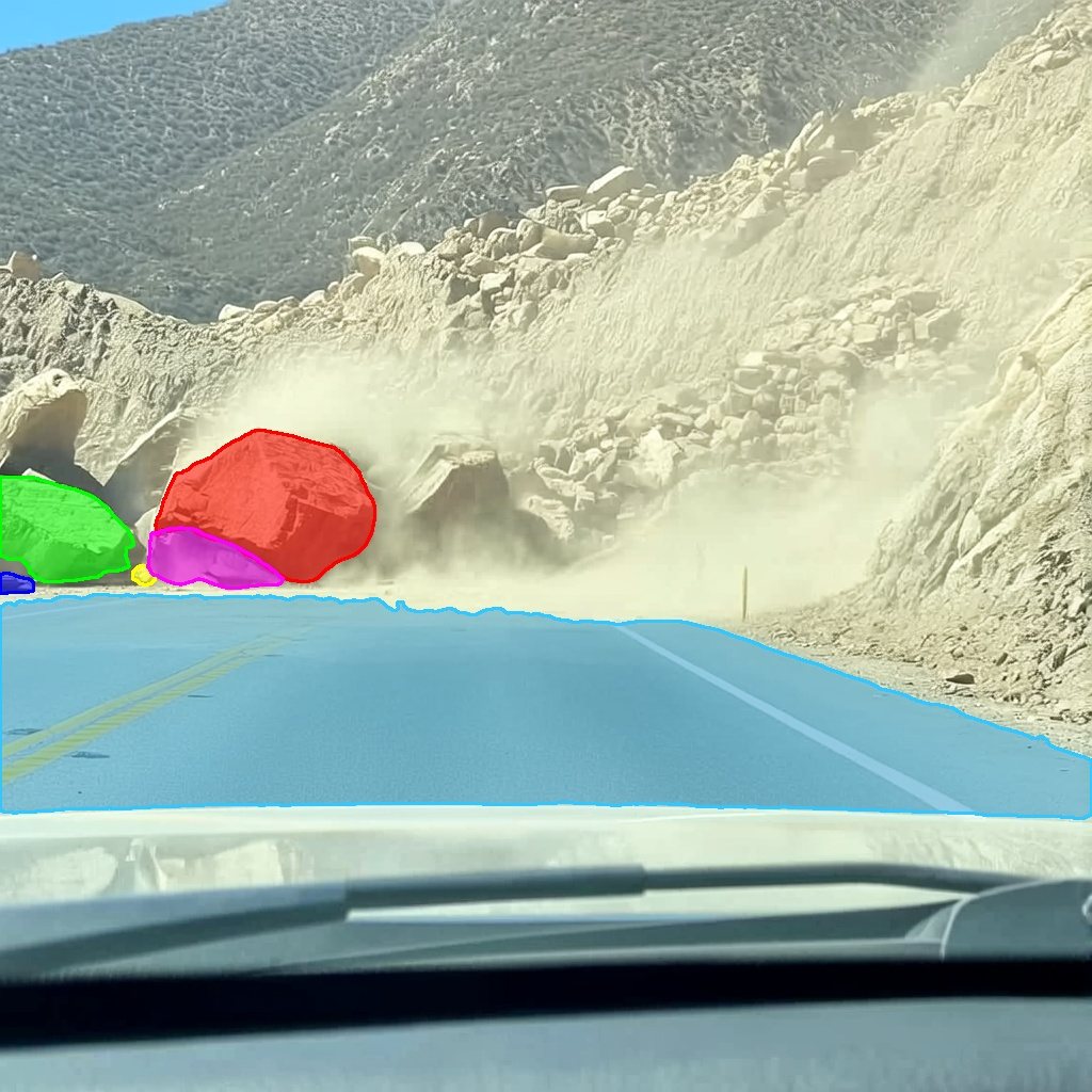Dashcam view of a rockfall on a mountain road with the road masked blue and each boulder masked in a separate colour