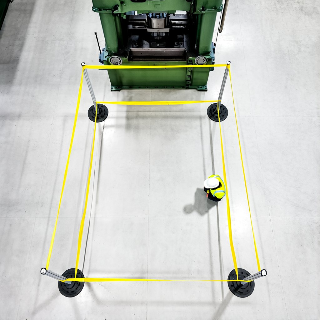 Factory floor with a press cordoned by yellow caution tape, a worker standing inside the cordon